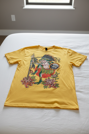 Yellow t-shirt with a colorful graphic design featuring a creature, flowers, and a skull on a white background.