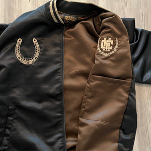 Close-up of satin fabric texture and embroidered horse detail on the bomber.