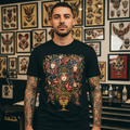 Laurent Trelaun Familiar Vase T-Shirt in Black featuring floral vase artwork with illustrated faces, worn by a model in a tattoo studio