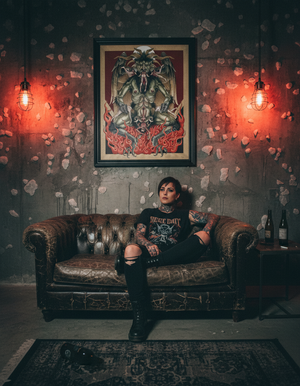 Person sitting on a vintage couch in a room with dark walls, a large framed poster, and dim lighting.
